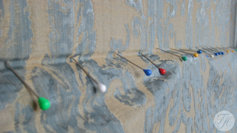 Detail van aanbrengen van wandbespanning, de luxe stof wordt eerst op patroon en spanning gezet met spelden